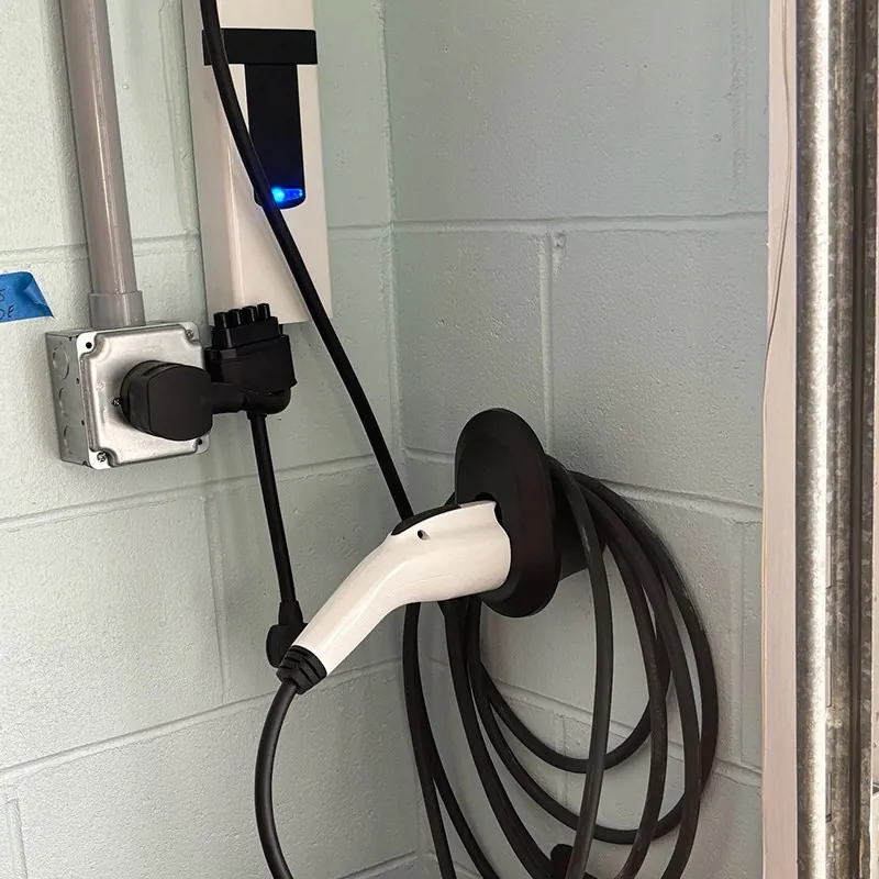 Wall-mounted EV charger with its cable coiled in a garage