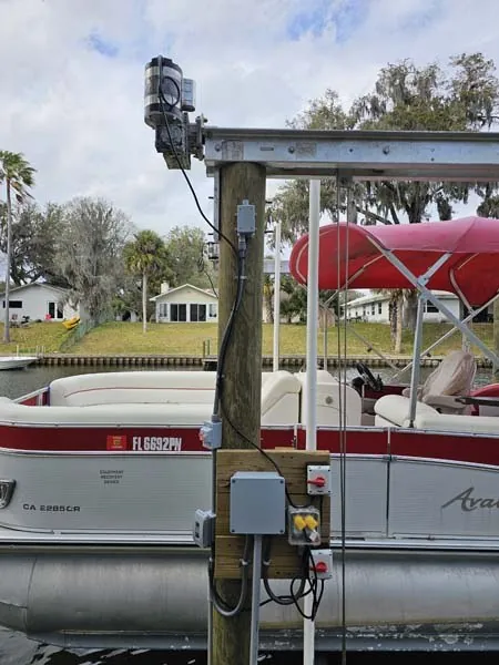 Pontoon boat on a canal-side lift, lift controls mounted on the piling